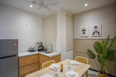 a kitchen with a table and a refrigerator and a sink at Neu Suites by COBNB in Kuala Lumpur
