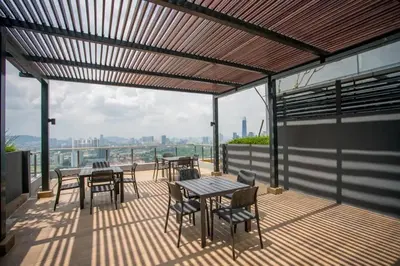 a patio with tables and chairs on a balcony at Neu Suites by COBNB in Kuala Lumpur
