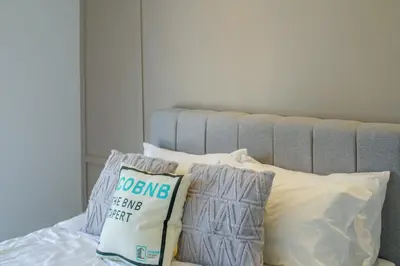 a bed with white pillows and a gray headboard at Neu Suites by COBNB in Kuala Lumpur