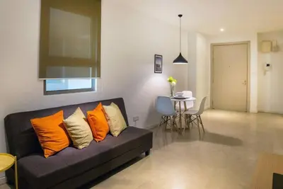 a living room with a black couch with orange pillows at Bintang Fairlane 2mins PavilionKL TRX KLCC - AJhome in Kuala Lumpur