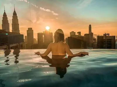 a woman sitting in a infinity pool looking at the city at Maxhome Plus @ The Platinum KLCC in Kuala Lumpur