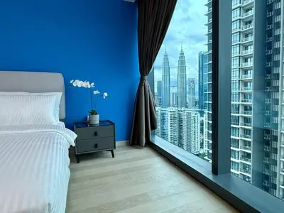 a blue bedroom with a bed and a large window at Eaton Residences KLCC in Kuala Lumpur