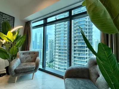 a living room with a chair and a large window at Eaton Residences KLCC in Kuala Lumpur