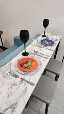 a marble table with two plates and wine glasses at The Nova by The City Collection in Kuala Lumpur