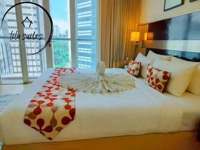 a bedroom with a large white bed with a large window at Lila Suites Seri Bukit Ceylon in Kuala Lumpur