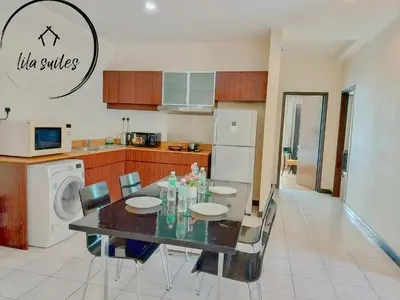 a dining room table with chairs and a kitchen at Lila Suites Seri Bukit Ceylon in Kuala Lumpur