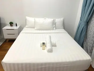 a white bed with two pillows and a remote on it at Summer Suites KLCC By Whollmark in Kuala Lumpur