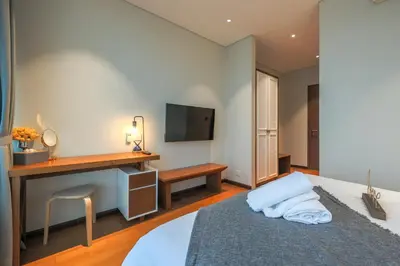 a bedroom with a bed with a desk and a television at Calm Sojourn, Sky Suites KLCC in Kuala Lumpur