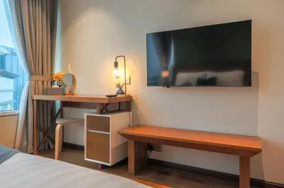 a hotel room with a desk and a television on the wall at Calm Sojourn, Sky Suites KLCC in Kuala Lumpur