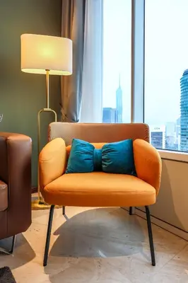 an orange chair with blue pillows in a room with a window at Calm Sojourn, Sky Suites KLCC in Kuala Lumpur