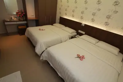 two beds in a hotel room with flowers on them at Tai Ichi Hotel Kuala Lumpur in Kuala Lumpur