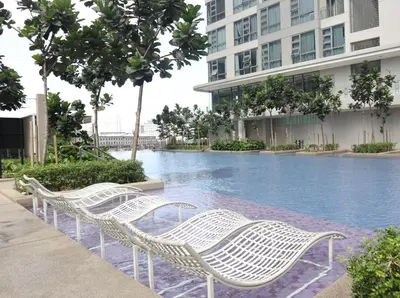 a row of white wicker chairs next to a swimming pool at MyCrib13*The Robertson KL - Bukit Bintang Pavilion in Kuala Lumpur