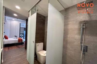 a bathroom with a shower and a toilet and a bedroom at NOVO Serviced Suites by Widebed, Jalan Ampang, Gleneagles in Kuala Lumpur