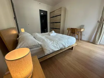 a bedroom with a bed with white sheets and a table at Muji Style, Inspirasi Residences Mont Kiara in Kuala Lumpur