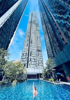 a woman in a swimming pool with two tall buildings at Star Residence Apartment with twin towers KLCC view in Kuala Lumpur