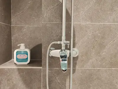 a shower with a bottle of soap on a shelf at The Axon Bukit Bintang by SMOVF BNB in Kuala Lumpur