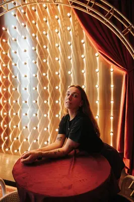 a woman sitting on a bed in front of a window at Scarletz Leisure Suites KLCC in Kuala Lumpur