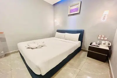 a bedroom with a bed with white sheets and flowers on it at Hotel Dlima Inn Bukit Bintang in Kuala Lumpur