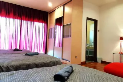 a bedroom with two beds and red curtains at KLCC Luxurious 2 Floors Homestay 5BR for 15pax in Kuala Lumpur