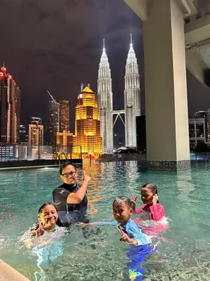 a man and children in a swimming pool in the city at Bricks & Beds Suite @ Legasi Kg Bahru in Kuala Lumpur