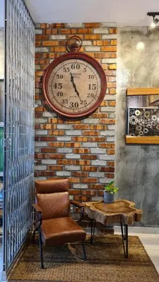 a clock on a brick wall with a chair and a table at Bricks & Beds Suite @ Legasi Kg Bahru in Kuala Lumpur