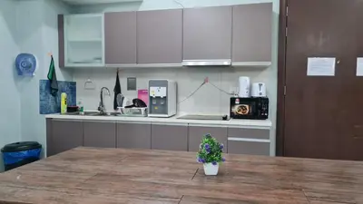 a kitchen with white cabinets and a table with a plant at Hostel At Regalia Sky Pool in Kuala Lumpur