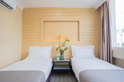 two beds in a room with a vase of flowers on a table at Hotel 28 Titiwangsa in Kuala Lumpur