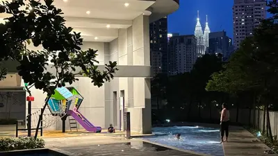 a person standing in a swimming pool with a kite at Balcony Unit @ Robertson Residence 18f in Kuala Lumpur
