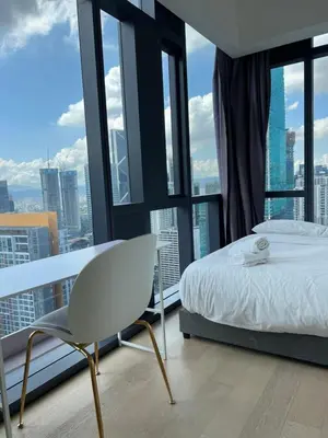 a bedroom with a bed and a chair in front of windows at Star residance at Klcc - Two bedrooms with twin towers view in Kuala Lumpur