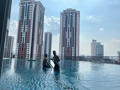 two people sitting in a infinity pool with a city skyline at Chambers Couple studio Klcc in Kuala Lumpur