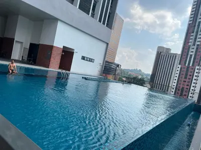 a man sitting on the edge of a swimming pool on a building at Chambers Couple studio Klcc in Kuala Lumpur