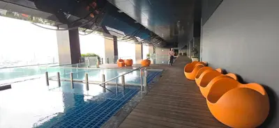 a swimming pool with orange chairs in a building at Panoramic KLCC Lake view, M CITY Jalan Ampang in Kuala Lumpur