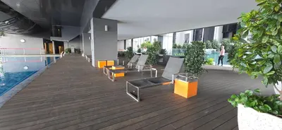 a building with a swimming pool and a deck with chairs at Panoramic KLCC Lake view, M CITY Jalan Ampang in Kuala Lumpur