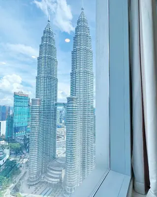 a view of three tall buildings from a window at Tropicana The Residence Hermes Suite with KLCC View in Kuala Lumpur