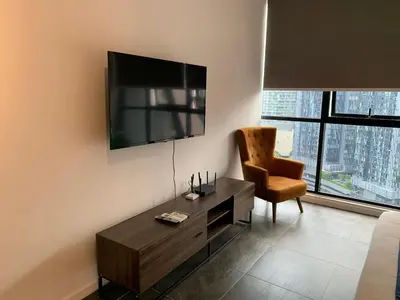 a living room with a tv and a chair at Scarletz Suites KLCC by GC Luxury Suites in Kuala Lumpur
