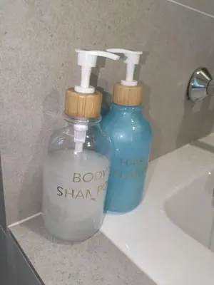 two bottles of soap sitting on a counter next to a sink at TheOoak suite 4pax cozy home stay @mont kiara in Kuala Lumpur