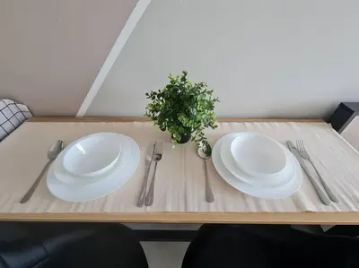 a wooden table with two white plates and silverware at 2R2B Apartment 10 mins to KLCC in Kuala Lumpur