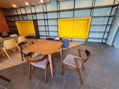 a room with tables and chairs and a yellow wall at 2R2B Apartment 10 mins to KLCC in Kuala Lumpur