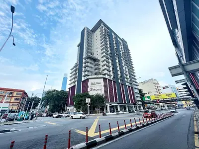 a large tall building on a city street with cars at Infini Suites@ D'Majestic Place Kuala Lumpur in Kuala Lumpur