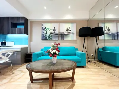 a living room with blue couches and a table with flowers at Infini Suites@ D'Majestic Place Kuala Lumpur in Kuala Lumpur