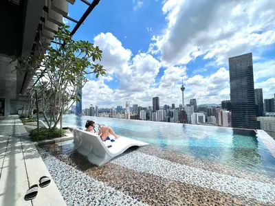 a man sitting in a bathtub on the edge of a swimming pool at Axon Bukit Bintang Pavillion KL KLCC by GoMain in Kuala Lumpur