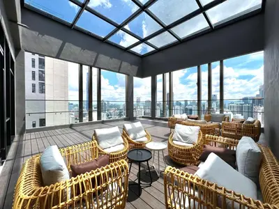 a balcony with wicker chairs and tables and windows at Axon Bukit Bintang Pavillion KL KLCC by GoMain in Kuala Lumpur