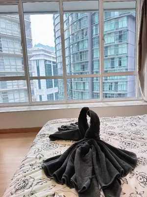 a blanket on a bed in front of a window at Park View KLCC ,by DeLive Home in Kuala Lumpur