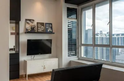 a living room with a flat screen tv and two windows at Park View KLCC ,by DeLive Home in Kuala Lumpur