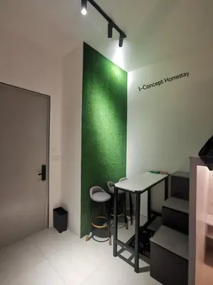 a room with a green wall and a table and stools at I-Concept Homestay in Kuala Lumpur