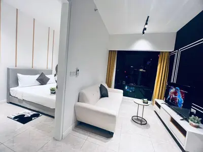 a white room with a bed and a chair and a tv at Axon Serviced Suites Kuala Lumpur in Kuala Lumpur