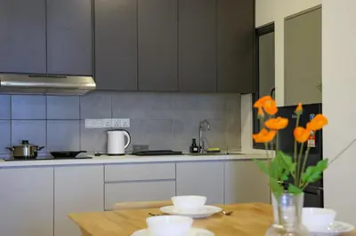 a kitchen with a table with a vase of orange flowers at Lovely 3-bedroom w pool 7 pax - Jalan Cheras in Kuala Lumpur