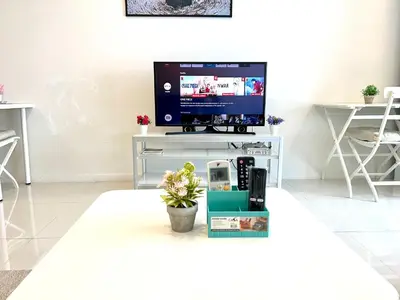 a living room with a television on a white table at Summer suites near klcc in Kuala Lumpur