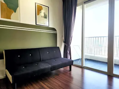 a black couch in a living room with a sliding glass door at Infini Suites@ UNA Residences, Sunway Velocity KL in Kuala Lumpur