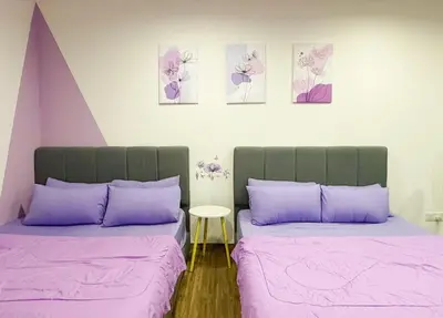 a bedroom with two beds with purple sheets and a table at SETAPAK CENTRAL KL - Lavender Zetapark Suite in Kuala Lumpur